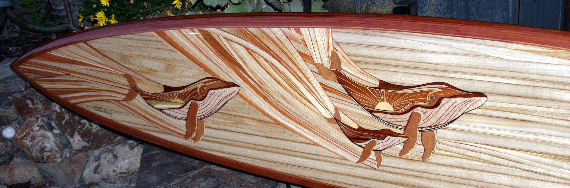 michael rumsey wood surfboard titled ohana with artwork depicting whales using only natural colors from reclaimed lumber