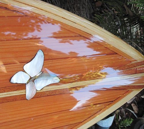 A beautiful wood inlay surfboard with abalone butterflies on it