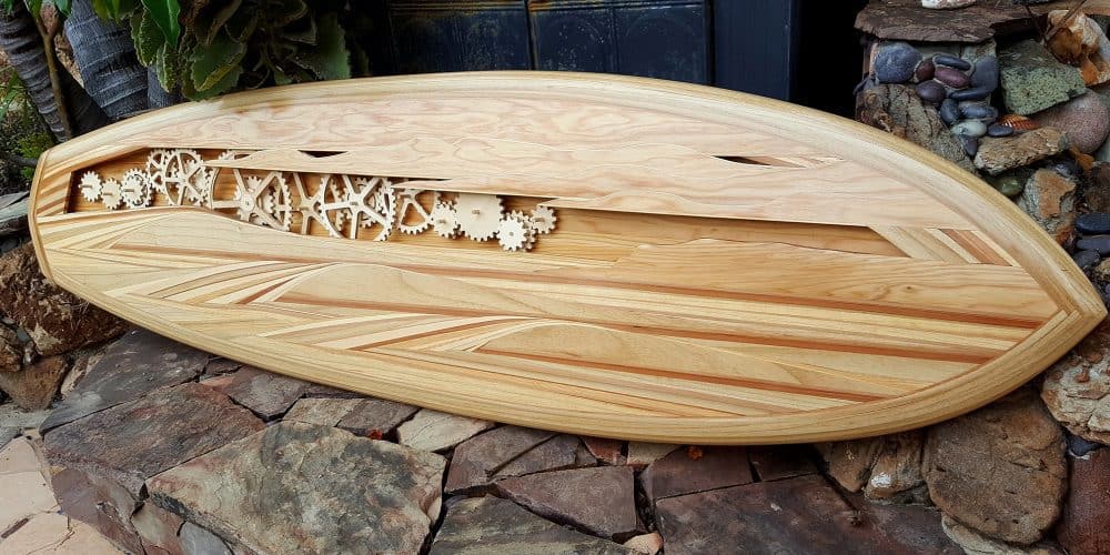 A wood inlay surfboard with cut outs of gears in it