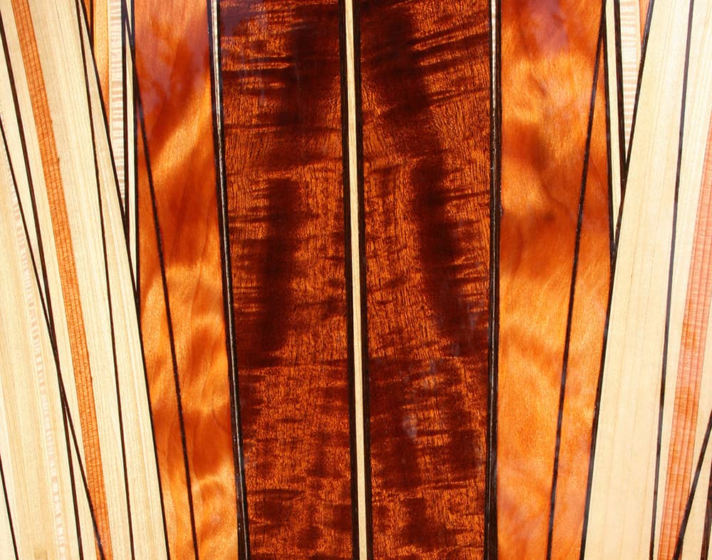 close up of koa wood insert in wood surfboard titled viking handcrafted by artist michael rumsey